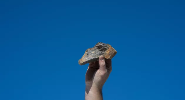 Sur gneis i form av bergart som holdes i hånden for illustrasjon