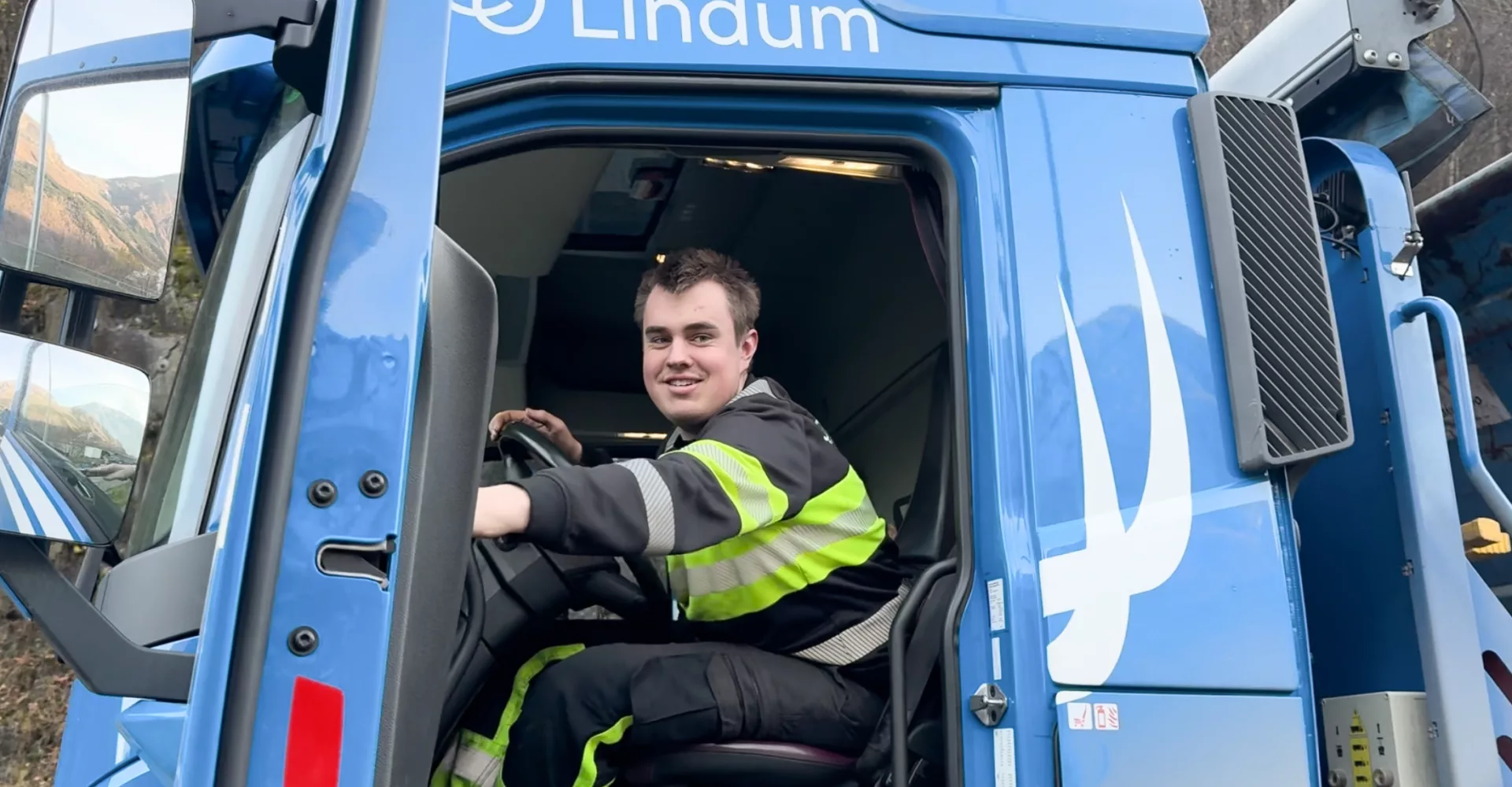 Mann smiler i lastebil og skal til å lukke døren.