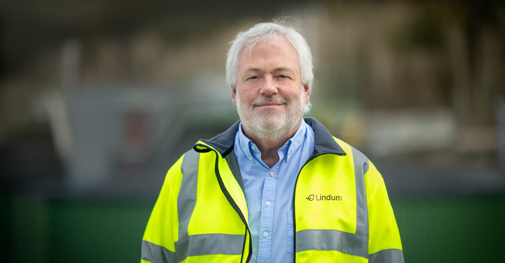 Pål Smits i skjorte og refleksjakke med biogassanlegg i bakgrunnen